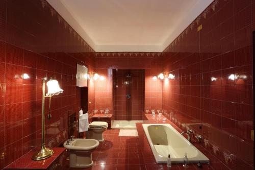 オルヴィエートにあるPalazzo Febeiの赤いタイル張りのバスルーム(トイレ、バスタブ付)