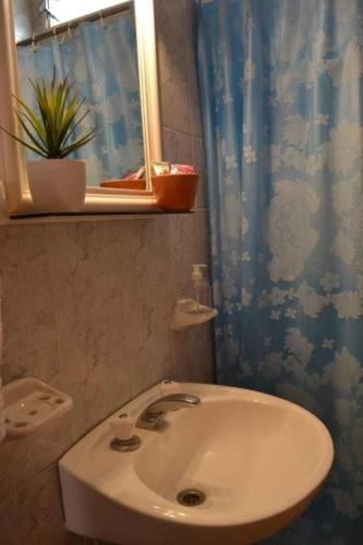 a bathroom with a sink and a blue shower curtain at Terraza del Sol Apart in San Juan