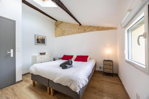 a bedroom with a bed with white sheets and red pillows at La Ferme - Château Le Noble in Saint-Germain-du-Puch