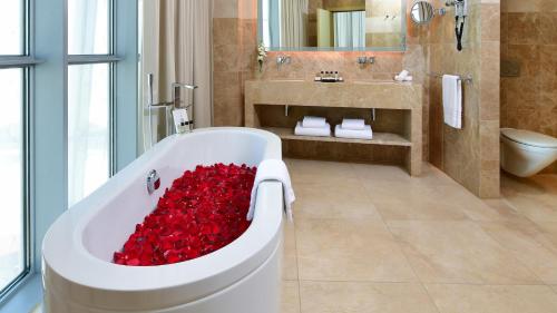 a bathroom with a tub filled with red roses at The Torch Doha in Doha