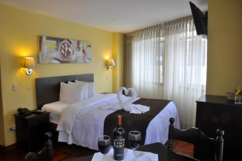 a hotel room with a bed with a bottle of wine at Casona Plaza Hotel Centro in Puno