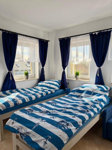 two beds in a bedroom with blue curtains at Tomaszówka in Sarbinowo