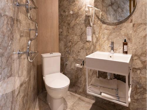 ein Badezimmer mit weißer Toilette und Waschbecken in der Unterkunft Health & Wellness Center Energetikas in Šventoji