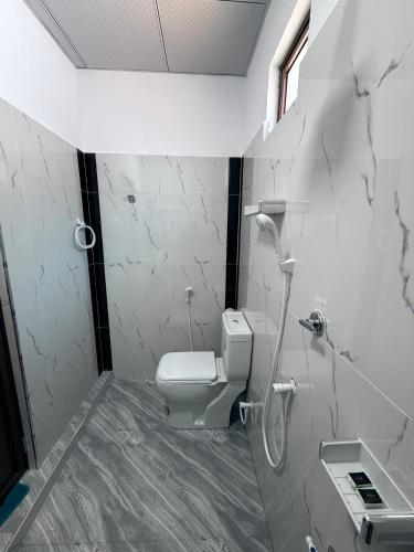 a white bathroom with a toilet and a sink at Diving Club Beach Resort in Trincomalee