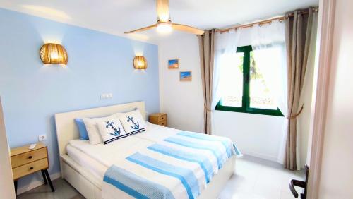 a blue bedroom with a bed and a window at La Maya in Caleta De Fuste