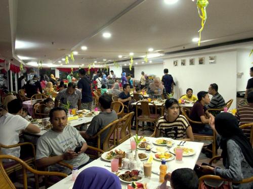 a group of people sitting at tables in a restaurant at Hotel Grand Continental Langkawi in Kuah