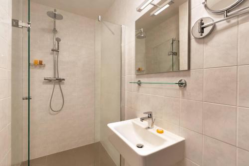 a white bathroom with a sink and a shower at Rotterdam Teleport Hostel in Rotterdam