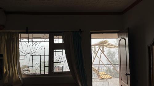 two windows in a room with a view of a playground at Aarroh villa in Coonoor