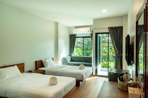 a hotel room with two beds and a chair at Sinai Rimtalay Hotel in Ban Nong Sanom