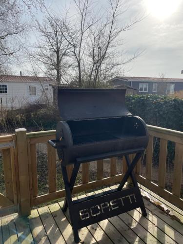 a grill sitting on a deck next to a fence at Chalet Pampusplaat 16 in Lauwersoog