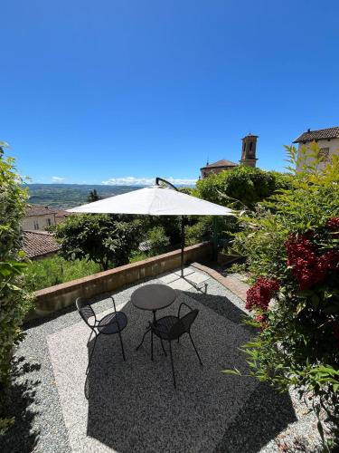 a patio with a table and chairs and an umbrella at An tij slè - Nel cuore del borgo in Guarene