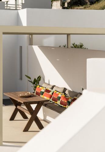 a table and a bench with pillows on a balcony at Blu Dot Tinos in Dhió Kkhoriá