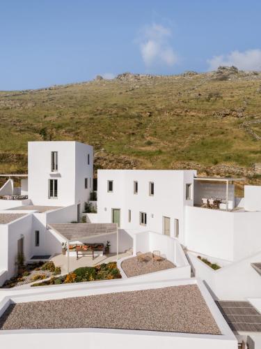 a cluster of white buildings with a hill in the background at Blu Dot Tinos in Dhió Kkhoriá