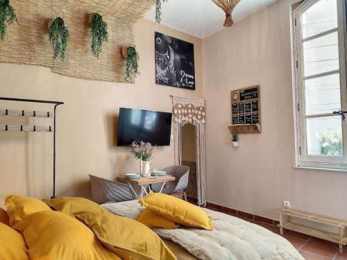 a room with a bed with yellow pillows and a tv at Cloître in Arles