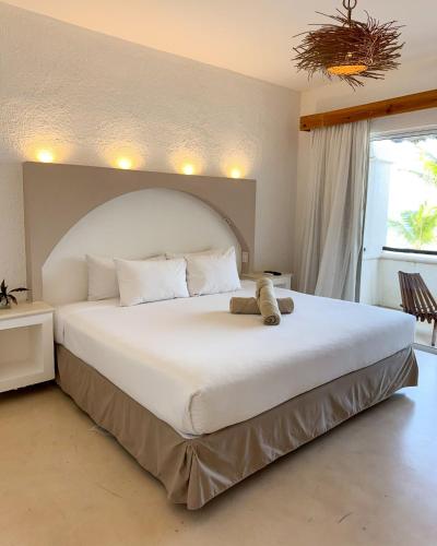 a large white bed with a teddy bear sitting on it at VR CLUB Tulum Riviera in Tulum