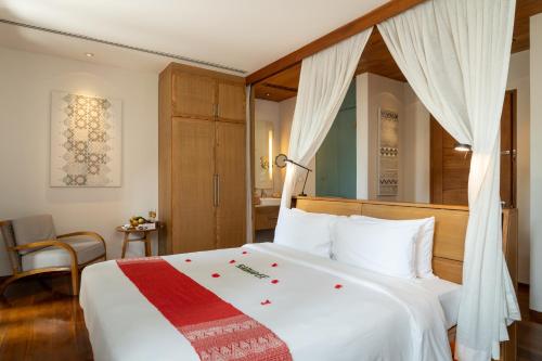 a bedroom with a white bed with a red and white blanket at Avani+ Luang Prabang Hotel in Luang Prabang