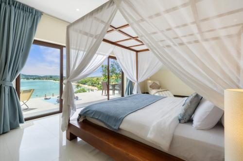 a bedroom with a canopy bed with a view of the ocean at Oceans Eleven Villa Samui - Oceanfront, Private Pool, Perfect for families and friends in Bangrak Beach