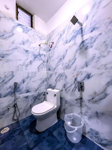 a bathroom with a toilet and a marble wall at Hotel Prime Access Inn in Indore