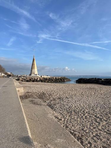 a beach with a lighthouse in the distance and a path at BluehousePortixol Mallorca in Palma de Mallorca