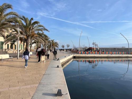 people walking on a sidewalk next to a body of water at BluehousePortixol Mallorca in Palma de Mallorca