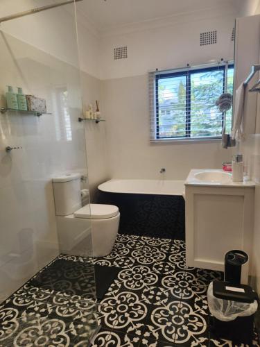 a bathroom with a tub and a toilet and a sink at Bowral Central Garden Apartment in Bowral