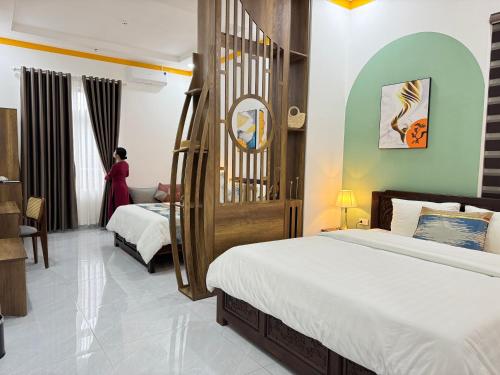 a hotel room with two beds and a woman in the window at ORCHID Hotel in Da Lat