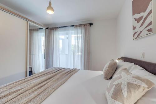 a bedroom with a white bed with a window at Apartmani Pocco Locco in Biograd na Moru