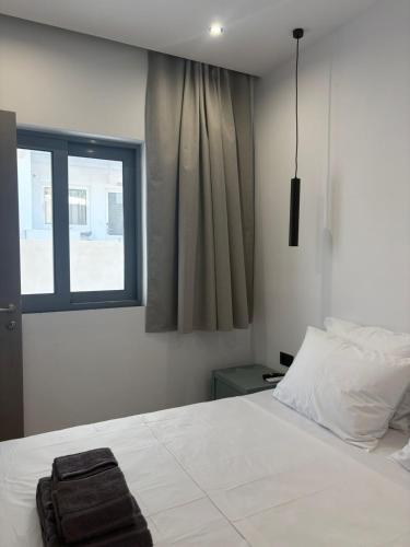 a bedroom with a white bed and a window at Coralli Beachfront in Pefki