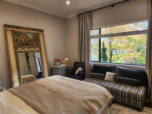 a bedroom with a bed and a mirror and a couch at Bowral Central Garden Apartment in Bowral