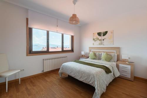 a white bedroom with a bed and a window at El Balcon de Moaña in Moaña