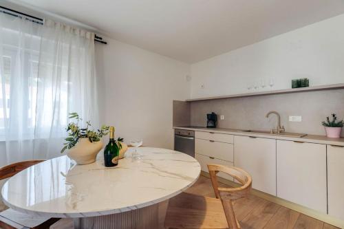 a white kitchen with a table and chairs and a sink at Apartmani Pocco Locco in Biograd na Moru