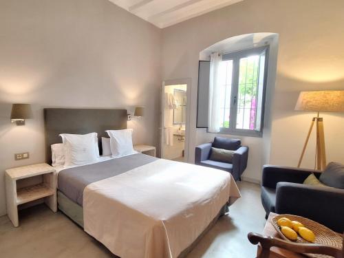 a bedroom with a bed and a chair and a window at Hotel Casa Calella in Calella de Palafrugell