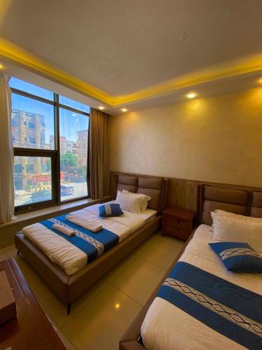 a bedroom with two beds and a large window at Al Mansi hotel in Amman