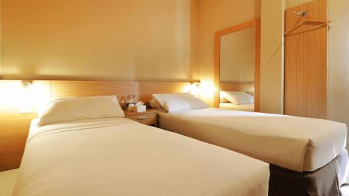 a hotel room with two beds and a mirror at Hotel Quds Express Syariah in Jakarta