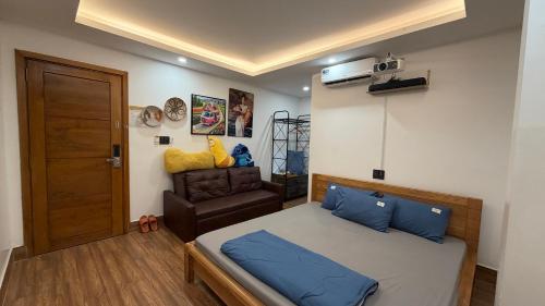 a bedroom with a bed with blue pillows and a chair at Nắng Hotel in Cẩm Mỹ