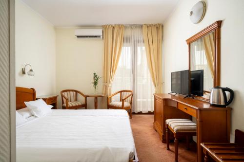 a hotel room with two beds and a desk with a television at Hotel Sarmis in Deva