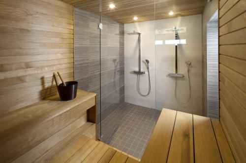 a bathroom with a shower with a glass door at Arkkitehtihuvila järvinäköalalla 5 makuuhuonetta ja tilauspalveluna ulkoporeallas in Ähtäri