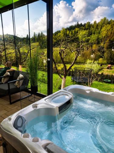 a jacuzzi tub in front of a large window at Cazare Colibita - Casa Lipan cu jacuzzi, foișor și loc de joacă in Colibiţa