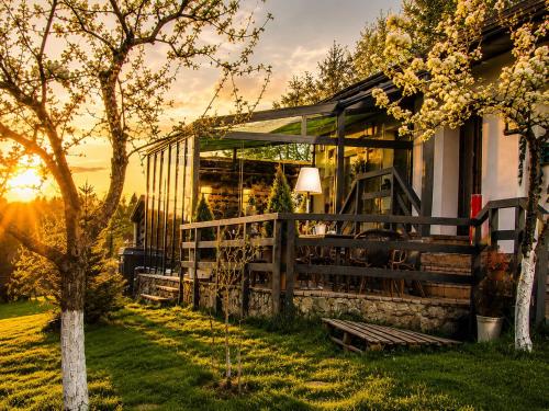 a house with the sun setting behind it at Cazare Colibita - Casa Lipan cu jacuzzi, foișor și loc de joacă in Colibiţa