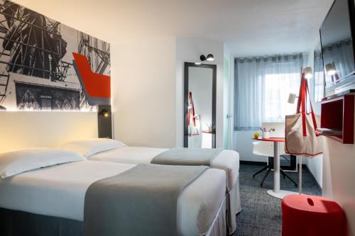 a hotel room with two beds and a desk at Hôtel Gustave Colmar in Colmar
