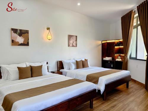 a hotel room with two beds and a window at New Sitơ Hotel in Quảng Ngãi