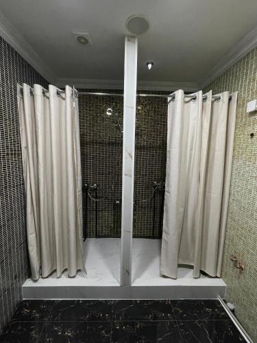 a shower with white curtains in a bathroom at ATB Grand Hostel in Atyrau