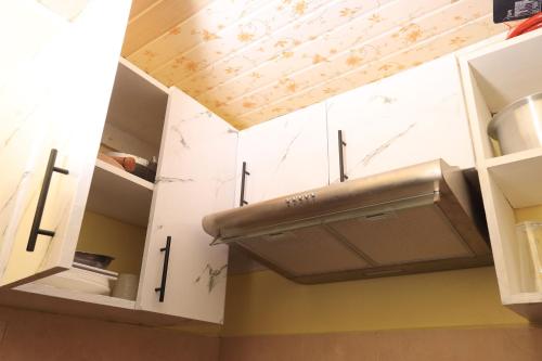 a kitchen with white cabinets and a hood at BomaZuri Homestays Tala in Nguluni