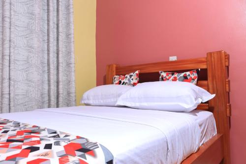 a bedroom with a bed with white and red walls at BomaZuri Homestays Tala in Nguluni