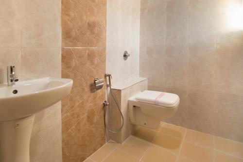 a bathroom with a toilet and a sink at Shoba Tulip Hebbal in Bengaluru
