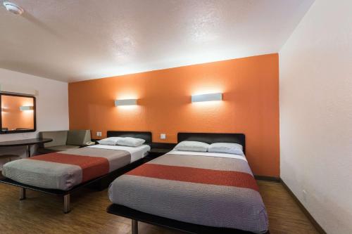 two beds in a room with an orange wall at Motel 6-Uvalde, TX in Uvalde