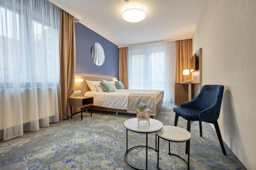 a hotel room with a bed and a chair and a table at Hotel Crystal in Hajdúszoboszló