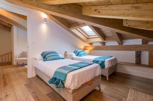 two beds in a attic room with wooden ceilings at Apartamentos La Botica in Comillas