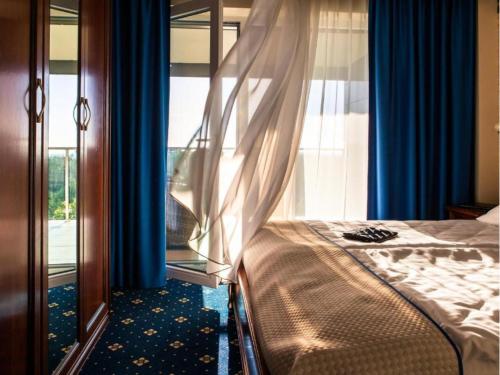 a bedroom with a bed and a window with blue curtains at SPA Amber Palace in Šventoji
