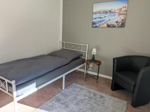a bed and a chair in a room at Lutz Appartements Südheide - Einzelzimmer in Gifhorn